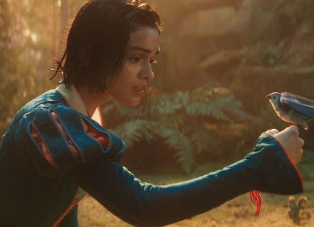 snow-white-review-girl-mom: A photo of Rachel Zegler as Snow White in the live action movie holding a blue bird.