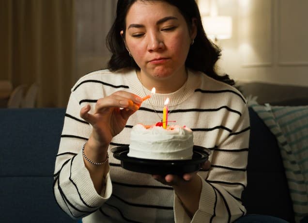 Woman somberly lights the candles for her birthday