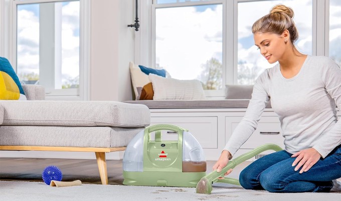 A woman using the Bissell Little Green Cleaner on a rug.