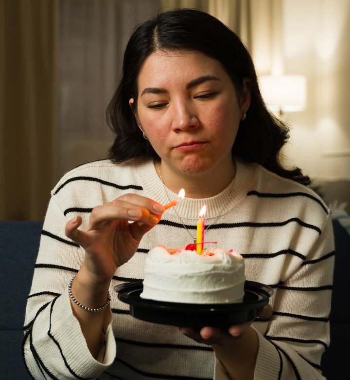 Woman somberly lights the candles for her birthday